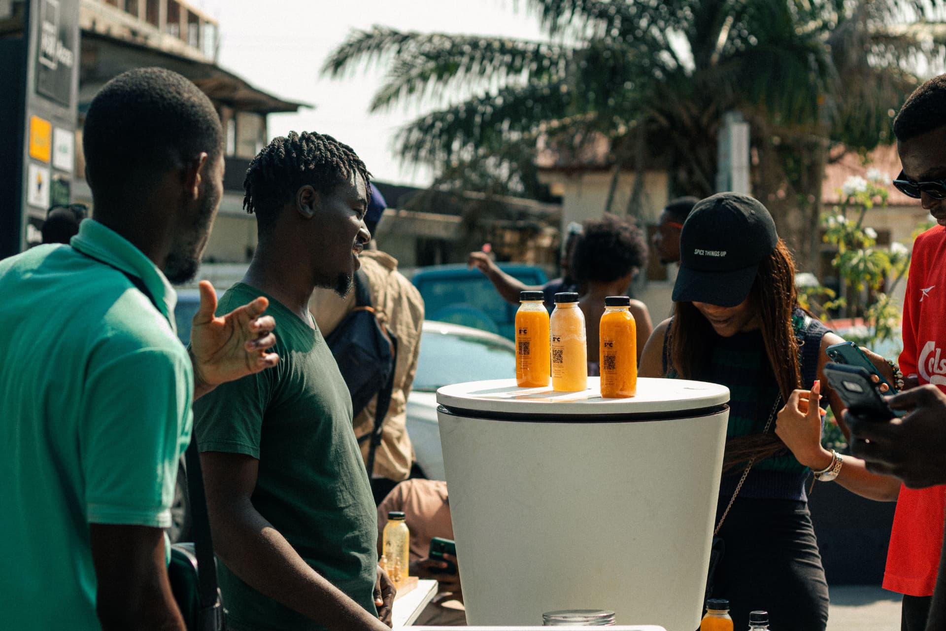 Customers buying bottles of Munchies fresh fruit juice at a street stand in Ghana